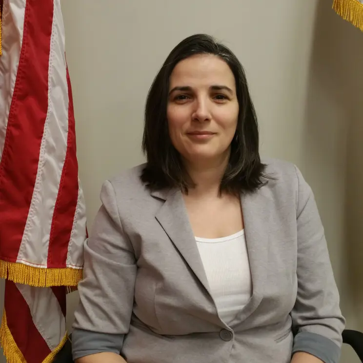 A photo of Purchasing Agent Simona Casian-Sirbu next to the American flag. 