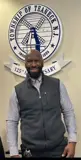 A photo of DPW Superintendent Travon Romeo standing in front of the Teaneck Seal and smiling. 